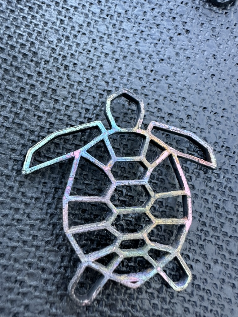 Geometric wireframe turtle print with iridescent blue, pink, and purple highlights on a dark surface
